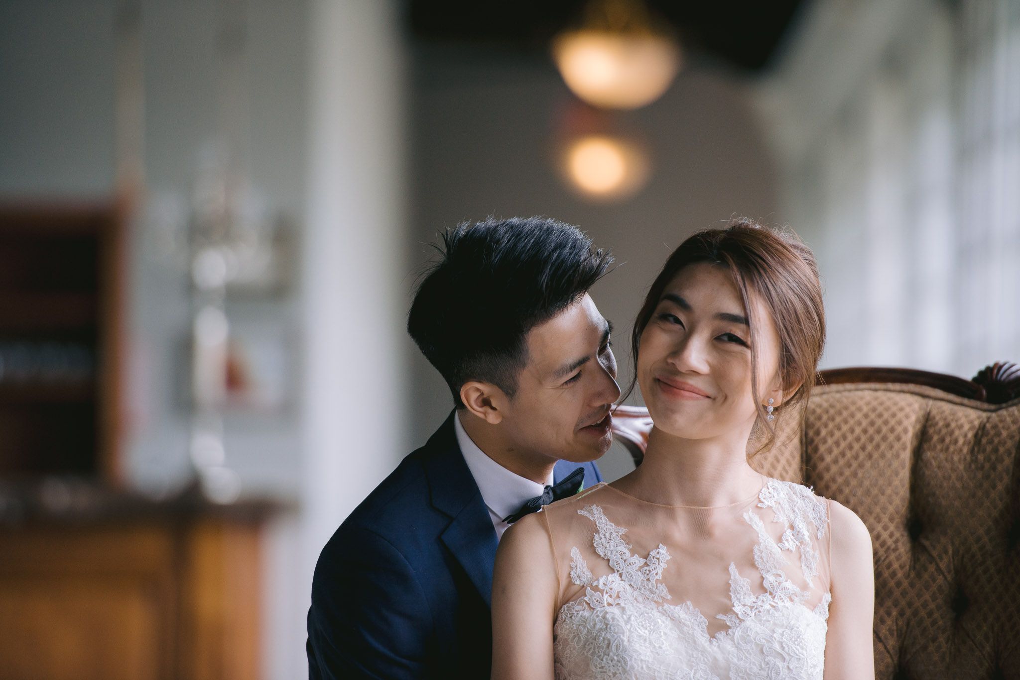 Intimate wedding portrait of couple sharing tender moment in elegant indoor setting.
