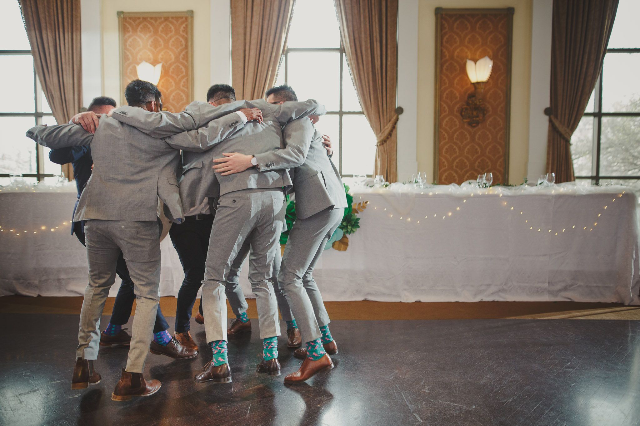 Groomsmen huddle together in a playful group pose during wedding celebrations.
