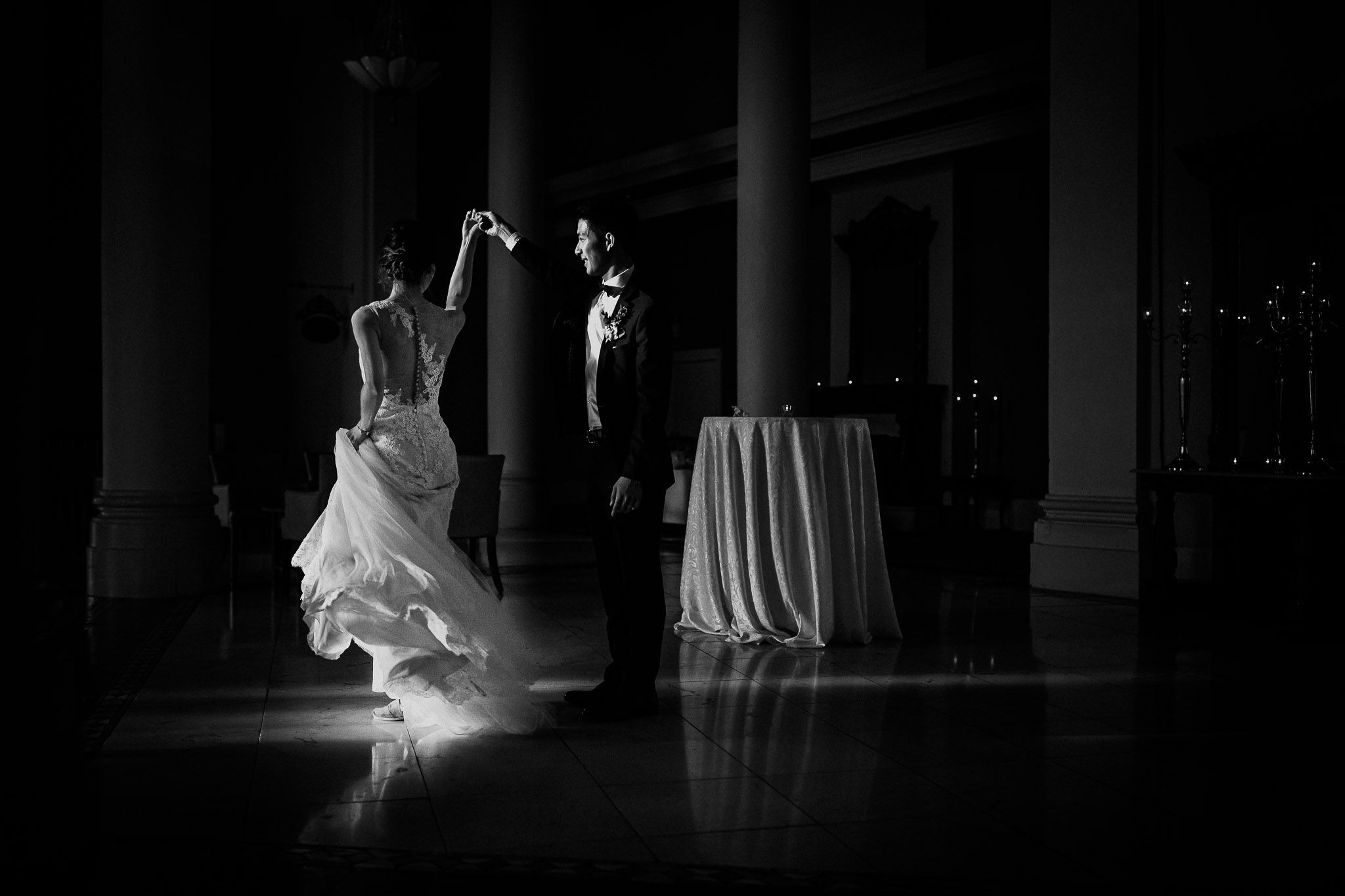 Dramatic black and white silhouettes of dancers in flowing gowns on a dark stage.