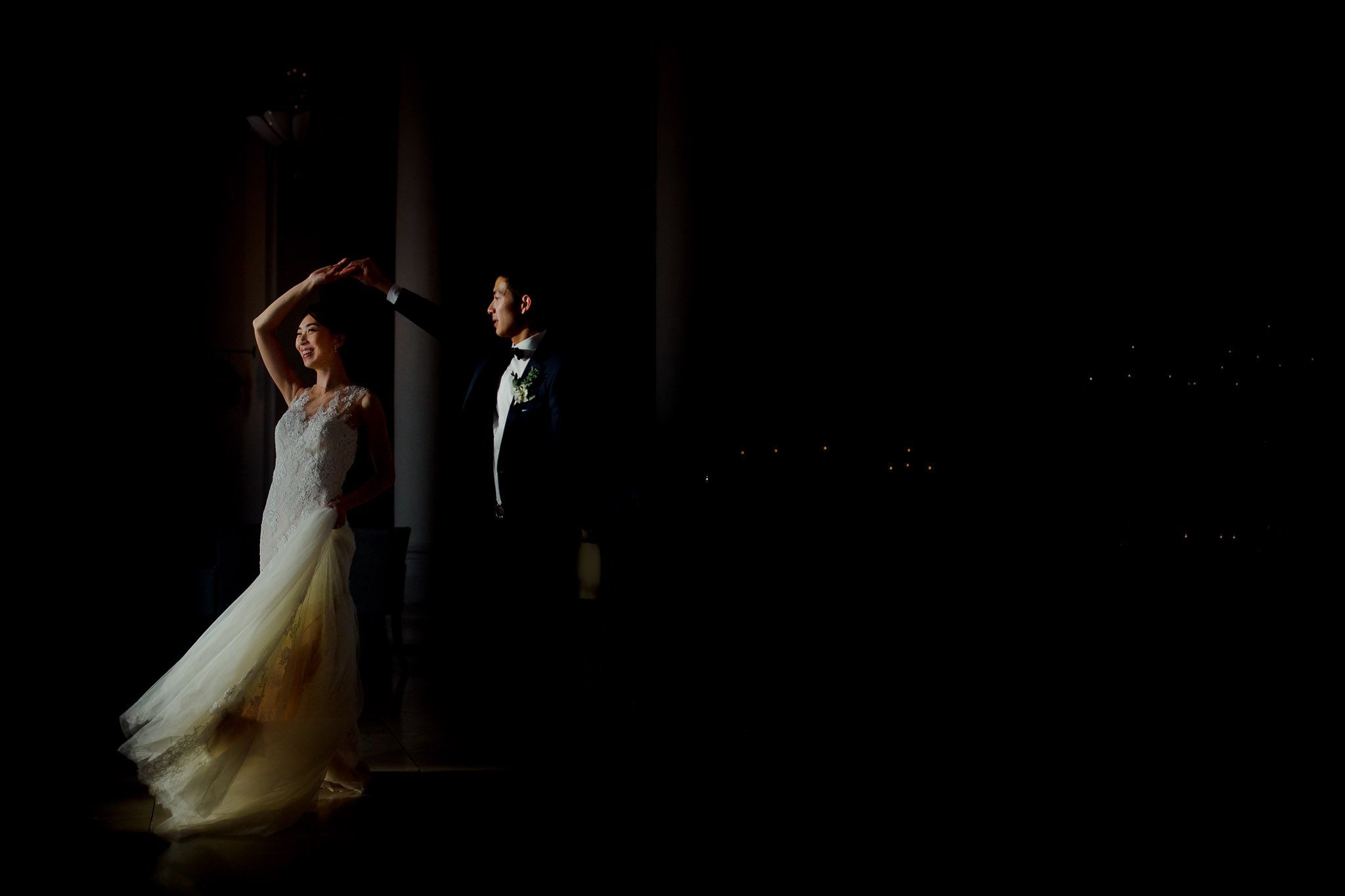 Silhouetted figures dance and celebrate in a darkened reception space with dramatic backlighting.