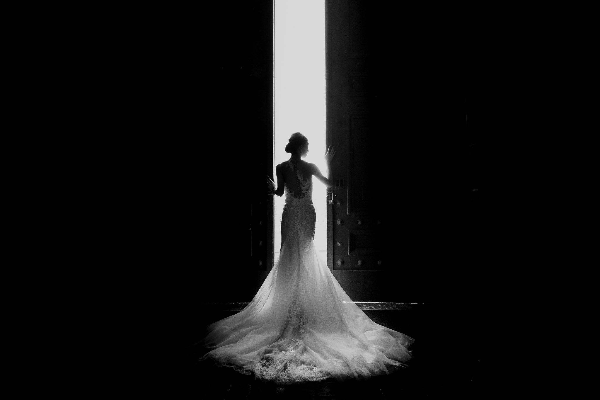 Ethereal black and white photo of a flowing wedding dress train in dramatic lighting.