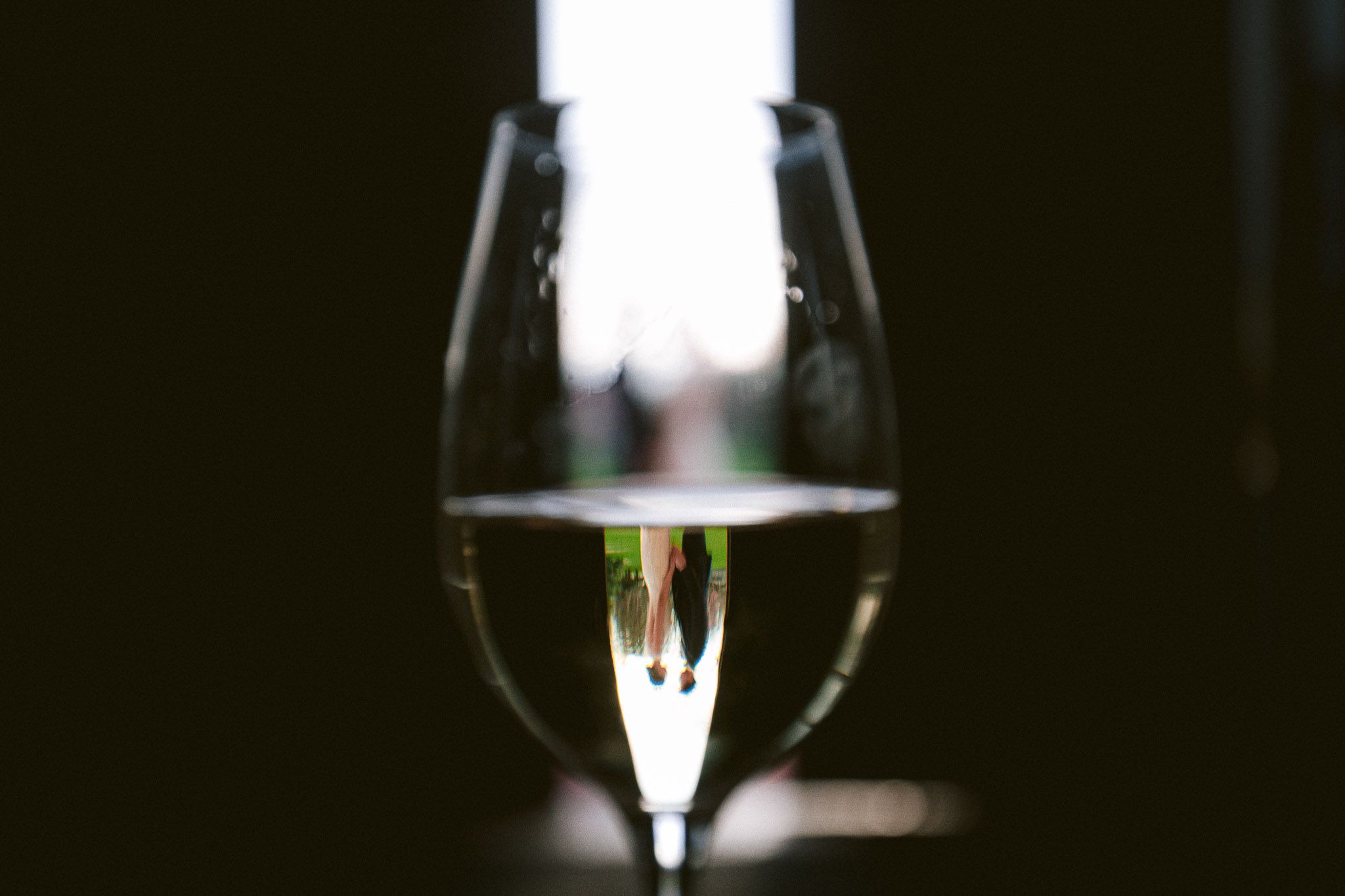 Wine glasses silhouetted against dark background create an elegant wedding reception ambiance.