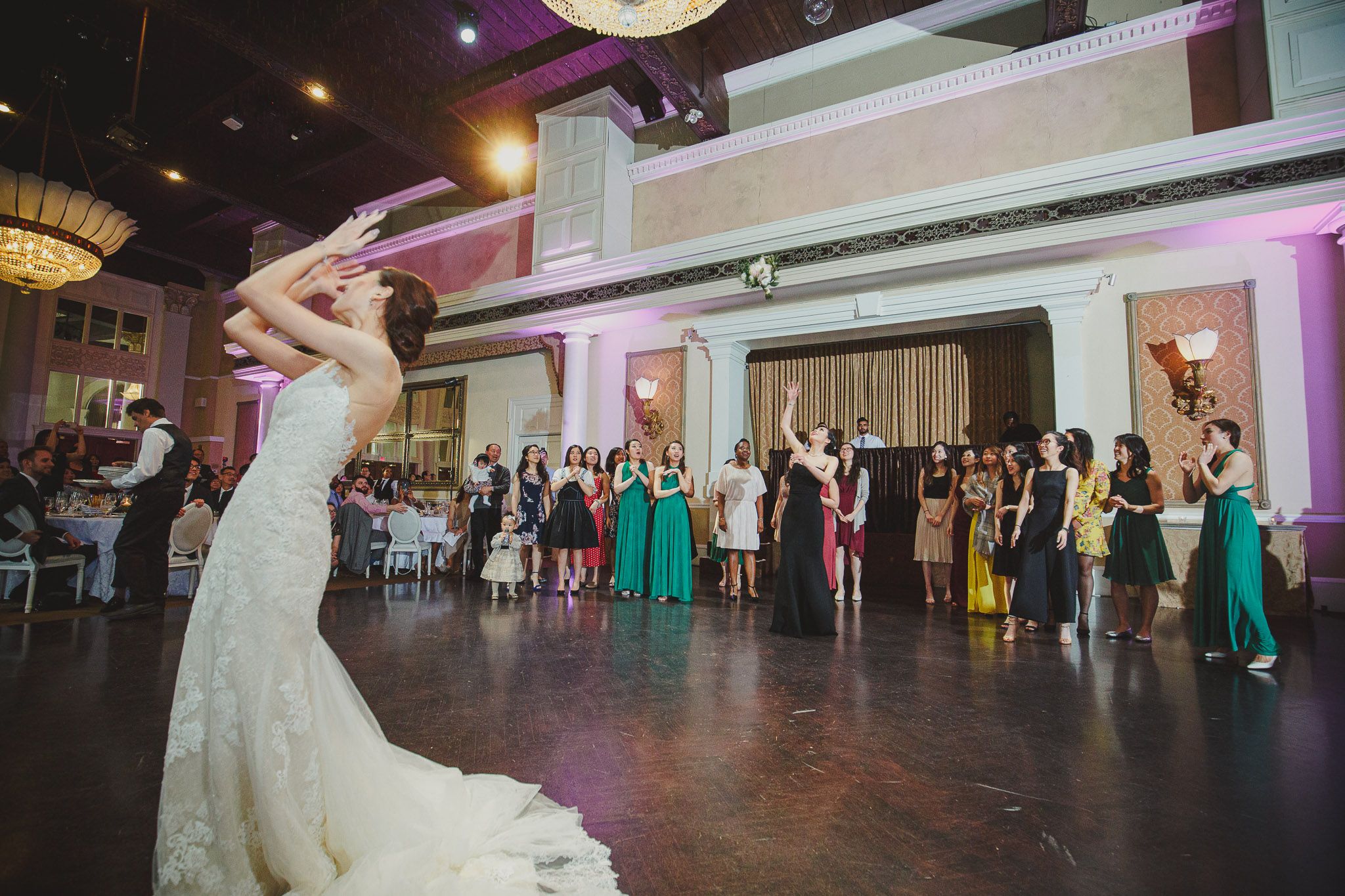 Wedding reception venue with guests dancing on a large dance floor under ambient lighting.