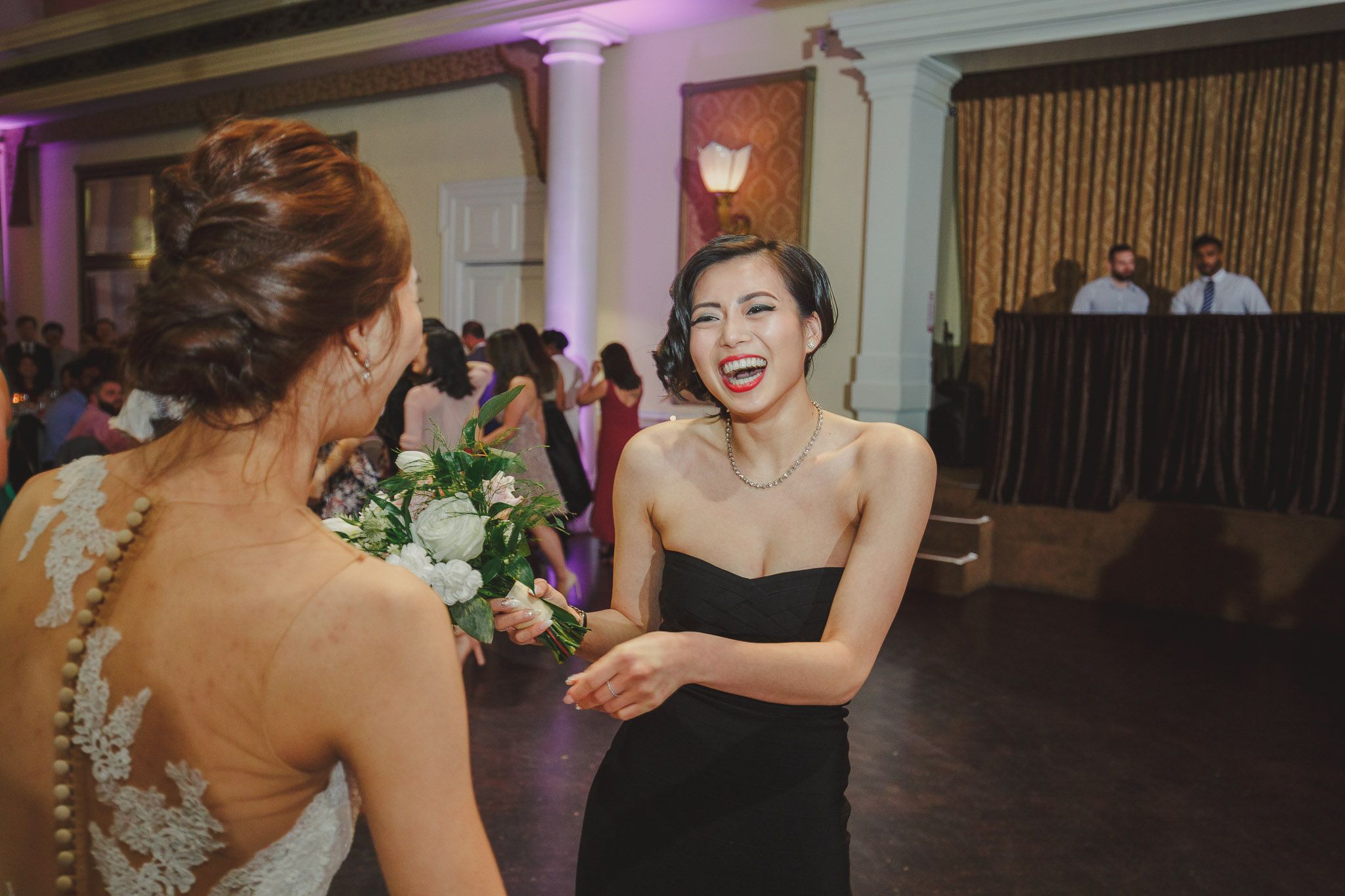Wedding celebration with guests dancing and enjoying festivities in an indoor reception hall.
