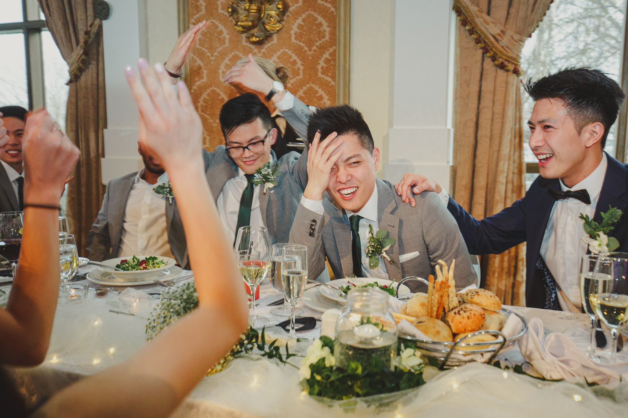 Wedding guests laugh and celebrate during a joyous reception dinner at an elegant venue.
