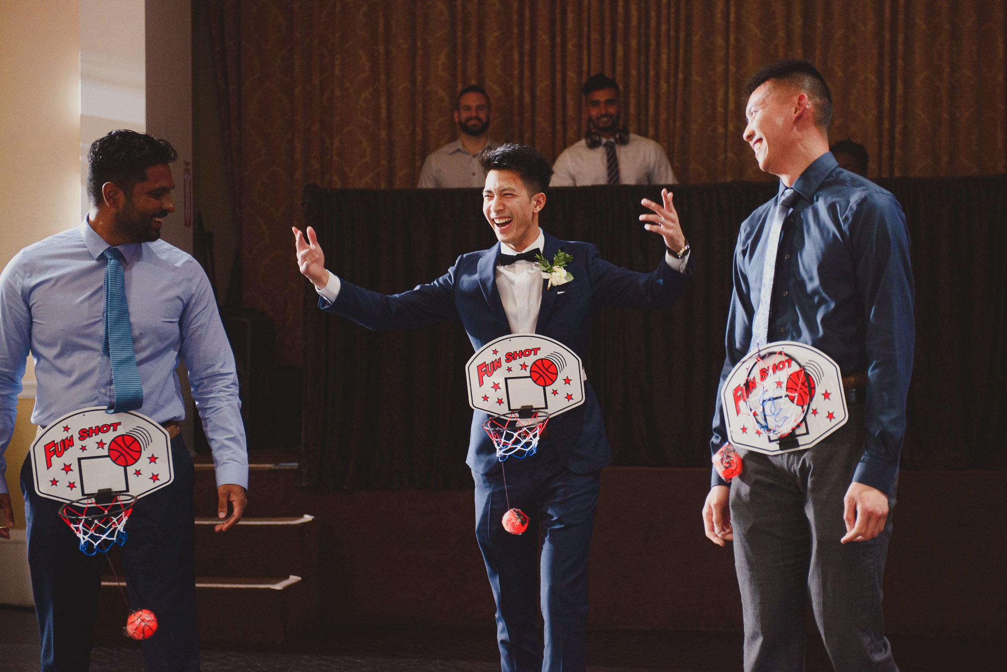 Guests at a wedding reception share drinks and laughter at a formal dinner table.