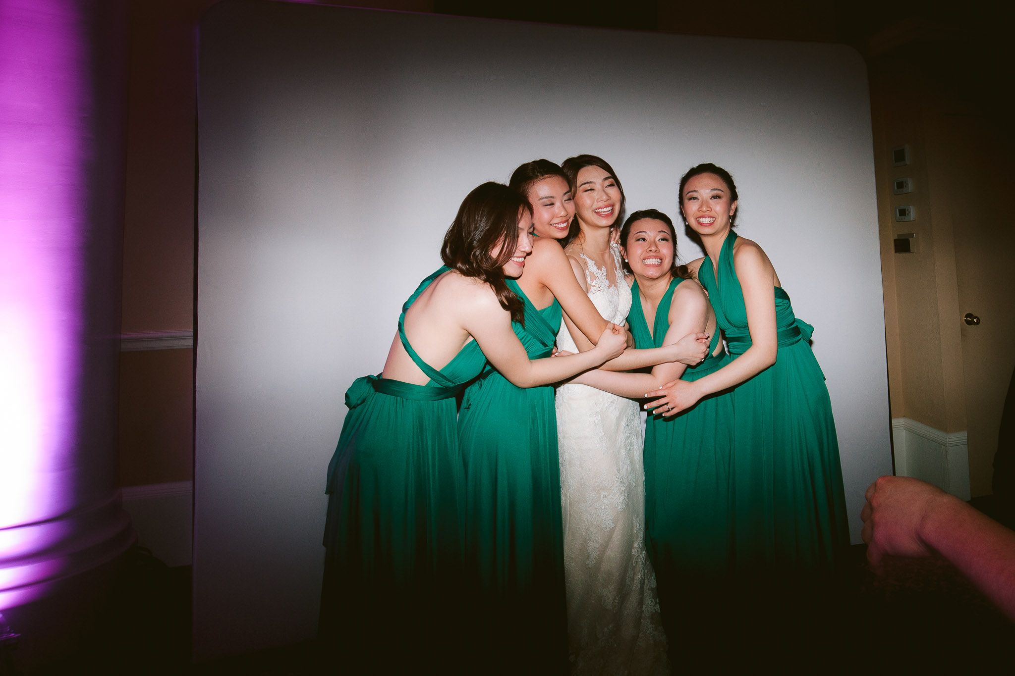 Wedding party members in emerald green dresses pose together during celebration.
