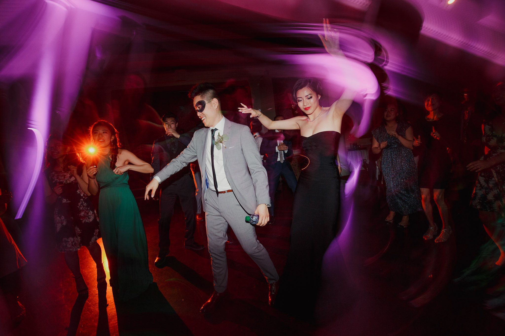 Wedding reception dance floor with purple lighting and silhouettes of people dancing.