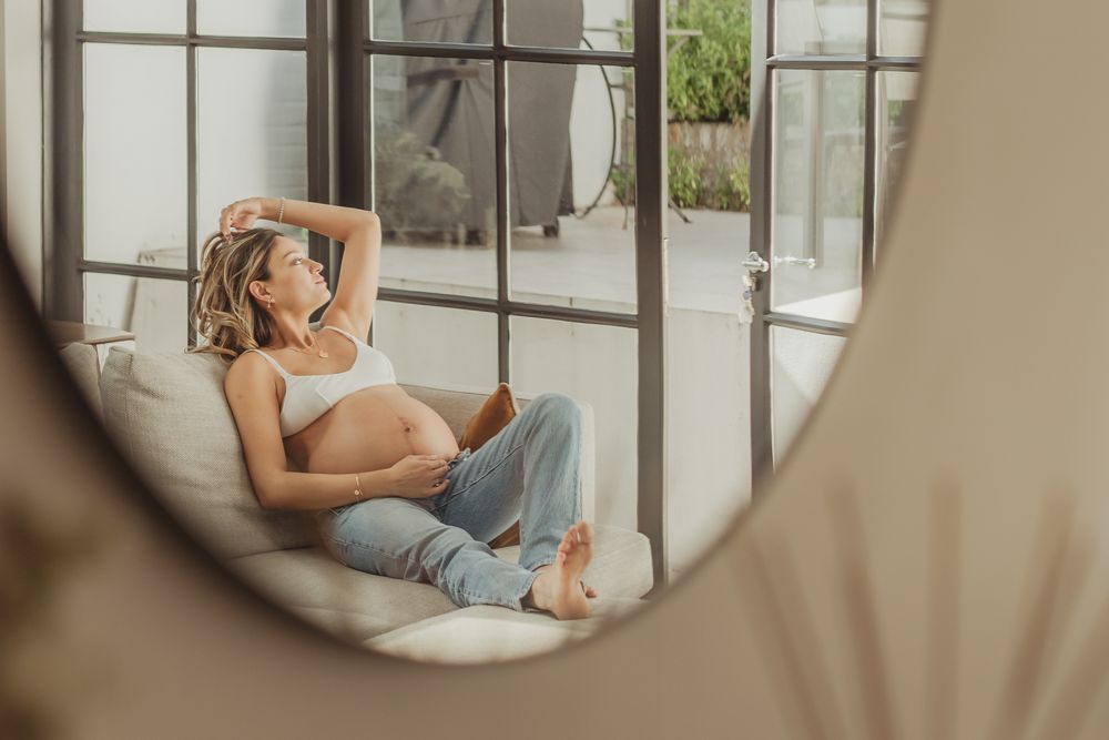 Artistic maternity photos taken in a modern room with large windows.