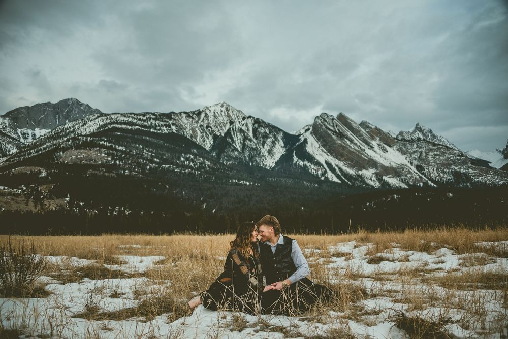 Snow-covered mountain range with tall peaks rising against a moody cloudy sky. Jasper Engagement Photographer