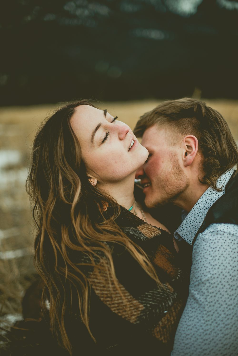 A romantic couple shares an intimate kiss outdoors, with soft moody lighting and natural scenery Jasper Engagement Photographer