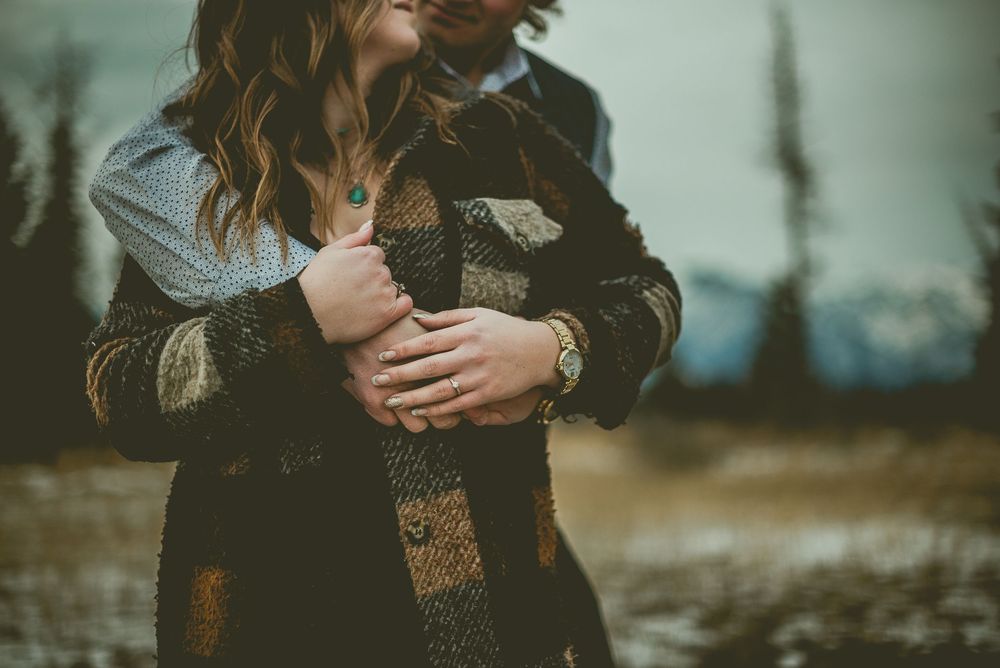 A couple embraces in a romantic outdoor setting at sunset with a soft bokeh effect in the background. Jasper Engagement Photographer