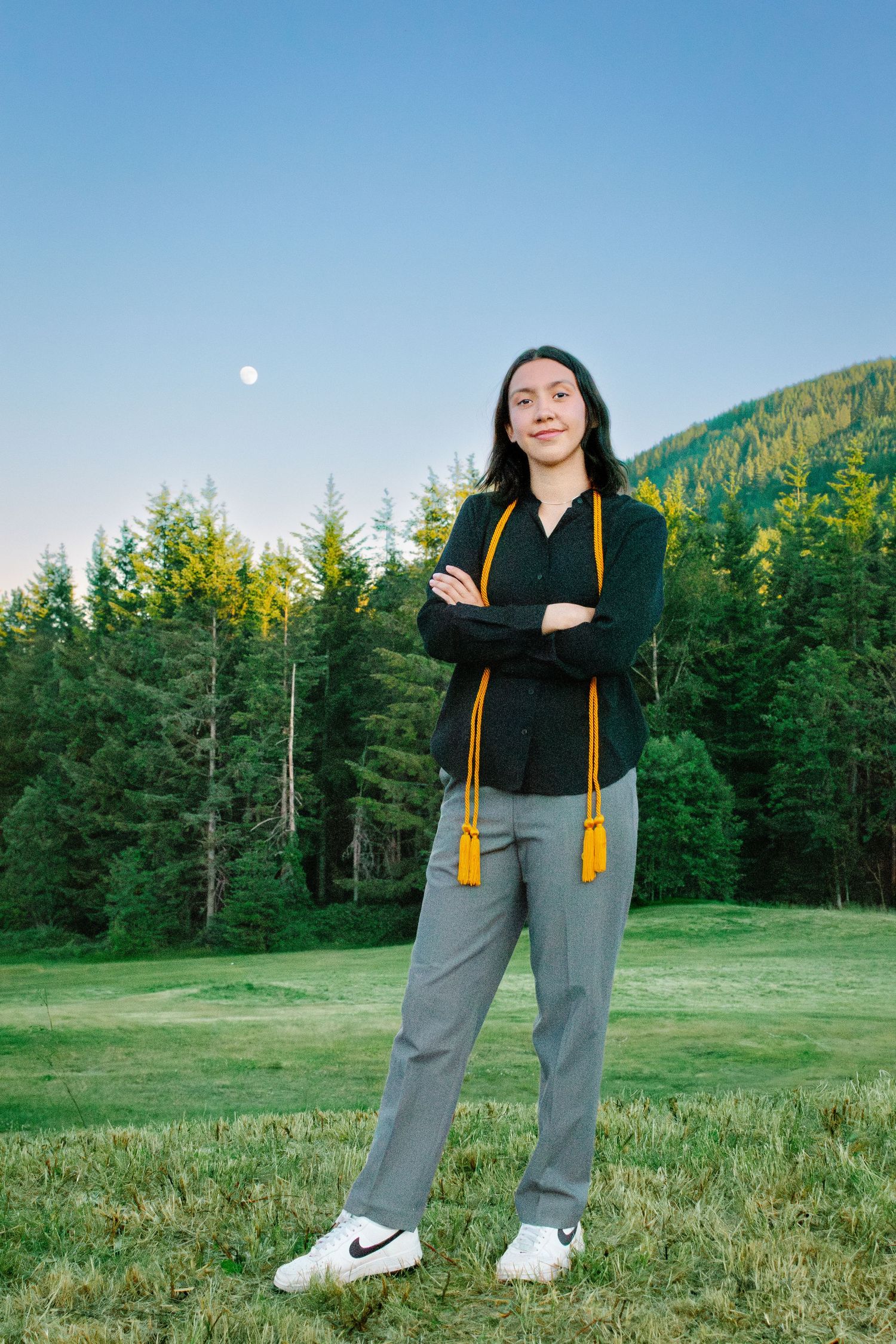 Senior portrait of Seattle student in slacks and graduation stole at Snoqualmie Point Park with mountain views.