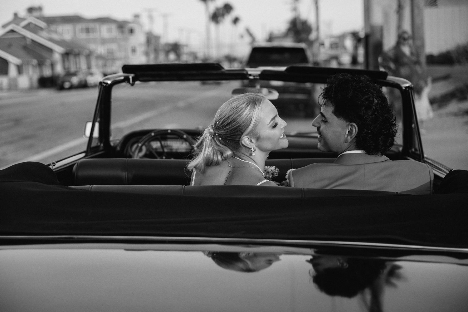 Classic convertible car driving scene in black and white with coastal road and ocean views.