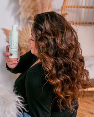 Hair styling demonstration with beauty products and wavy brown hair.