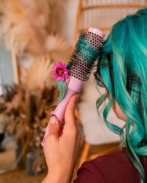 Close up of teal hair and studded accessories with pink flower detail.