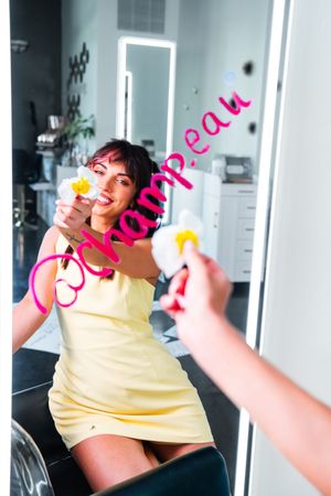 Person in yellow tank top posing playfully in studio setting.