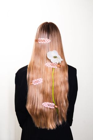 Long straight hair decorated with pink hair clips and flowers.