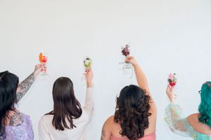 Row of people raising cocktail glasses in a festive toast.