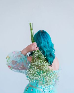 Ethereal poses with baby's breath flowers and turquoise hair against white background.