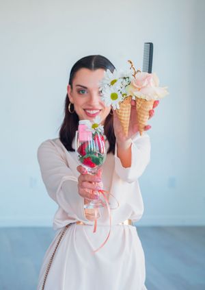 Person in white holding decorative drinks and ice cream cone props for styling.