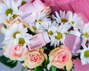 Flat lay of pink roses and white daisies with business cards arranged in a row.
