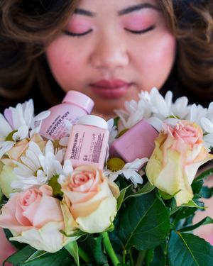Close-up of pink roses and daisies with business cards in soft lighting.