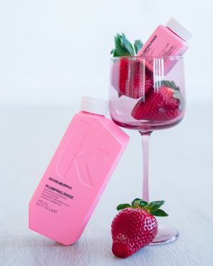Pink beauty product bottles with fresh strawberries on white background.