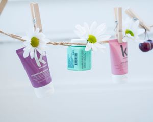Floating beauty product bottles in pastel colors against white background.
