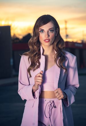 Stylish outdoor fashion shoot featuring pink blazer and crop top at sunset.