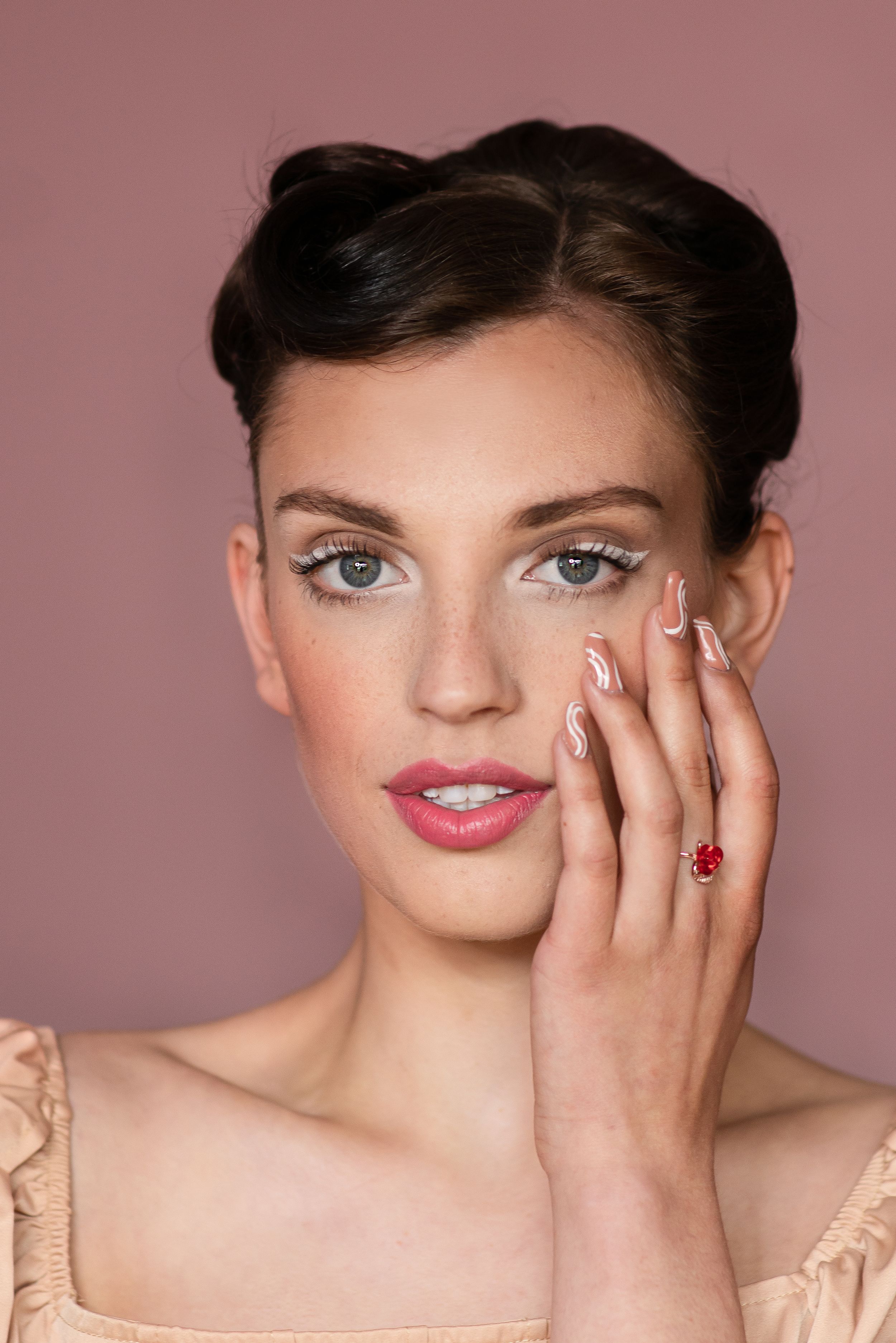 Close-up beauty portraits showing elegant makeup and manicured hands against pink background.
