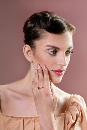 Fashion portrait with pink lipstick and delicate hand poses against soft pink background.
