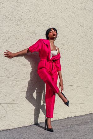 Street style photography featuring bold pink dress with dramatic poses against white wall.