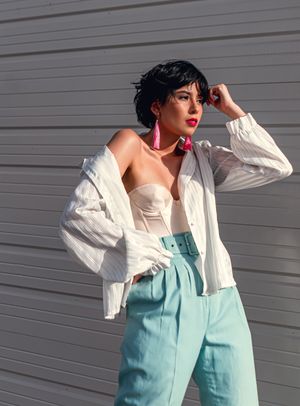 Fashion shoot featuring white blouse and mint pants against grey background with dramatic poses.