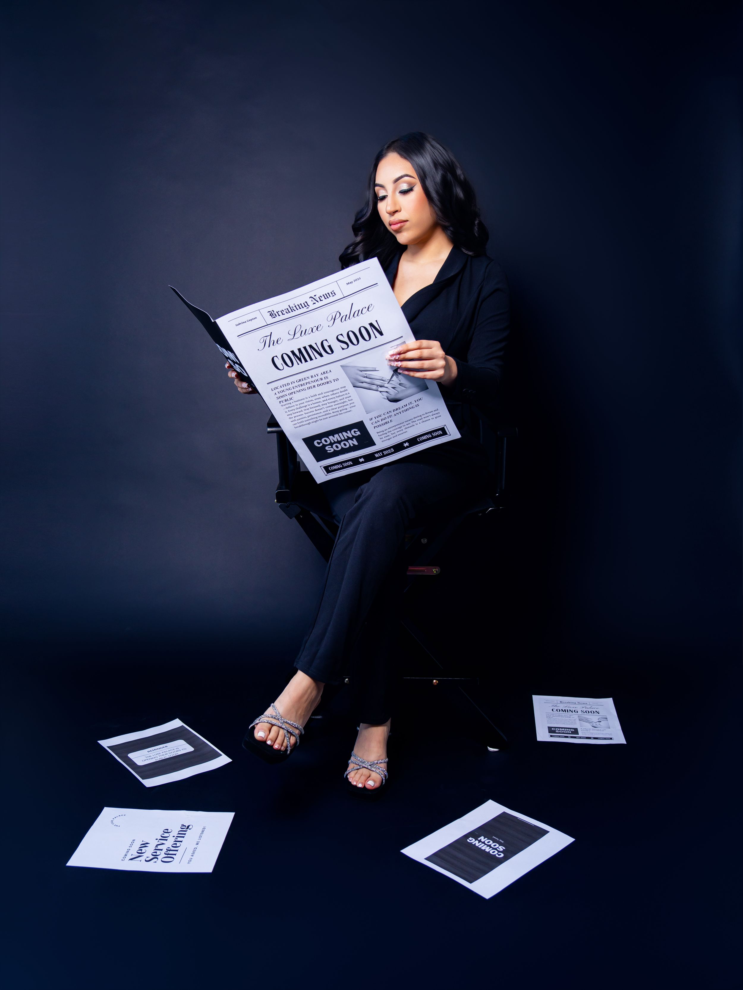 Artistic photoshoot with newspaper props against dark blue background.