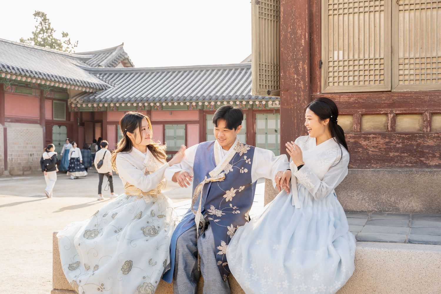 People in traditional hanbok clothing pose and play in a historic Korean palace courtyard.