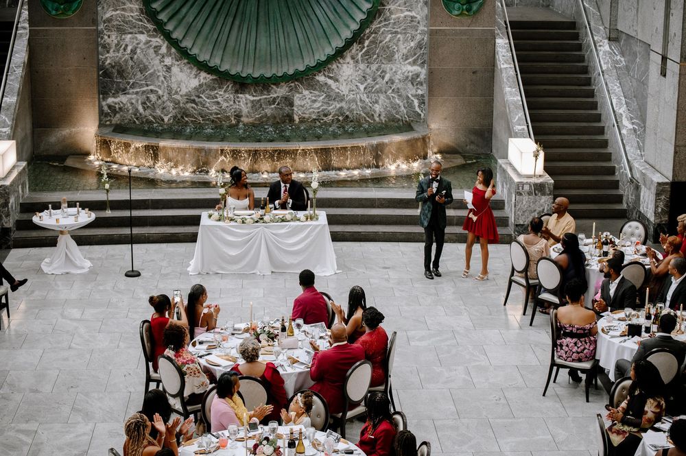 Wedding reception venue with green decor elements and marble walls filled with seated guests.