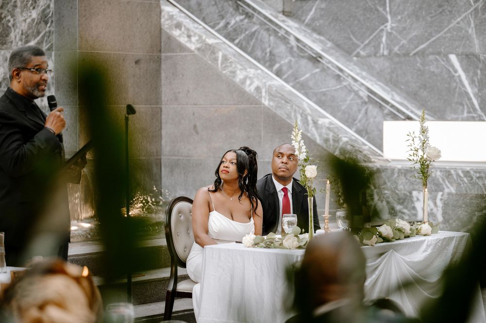 Modern wedding venue interior features gentle natural lighting streaming through glass ceiling panels and white table settings.