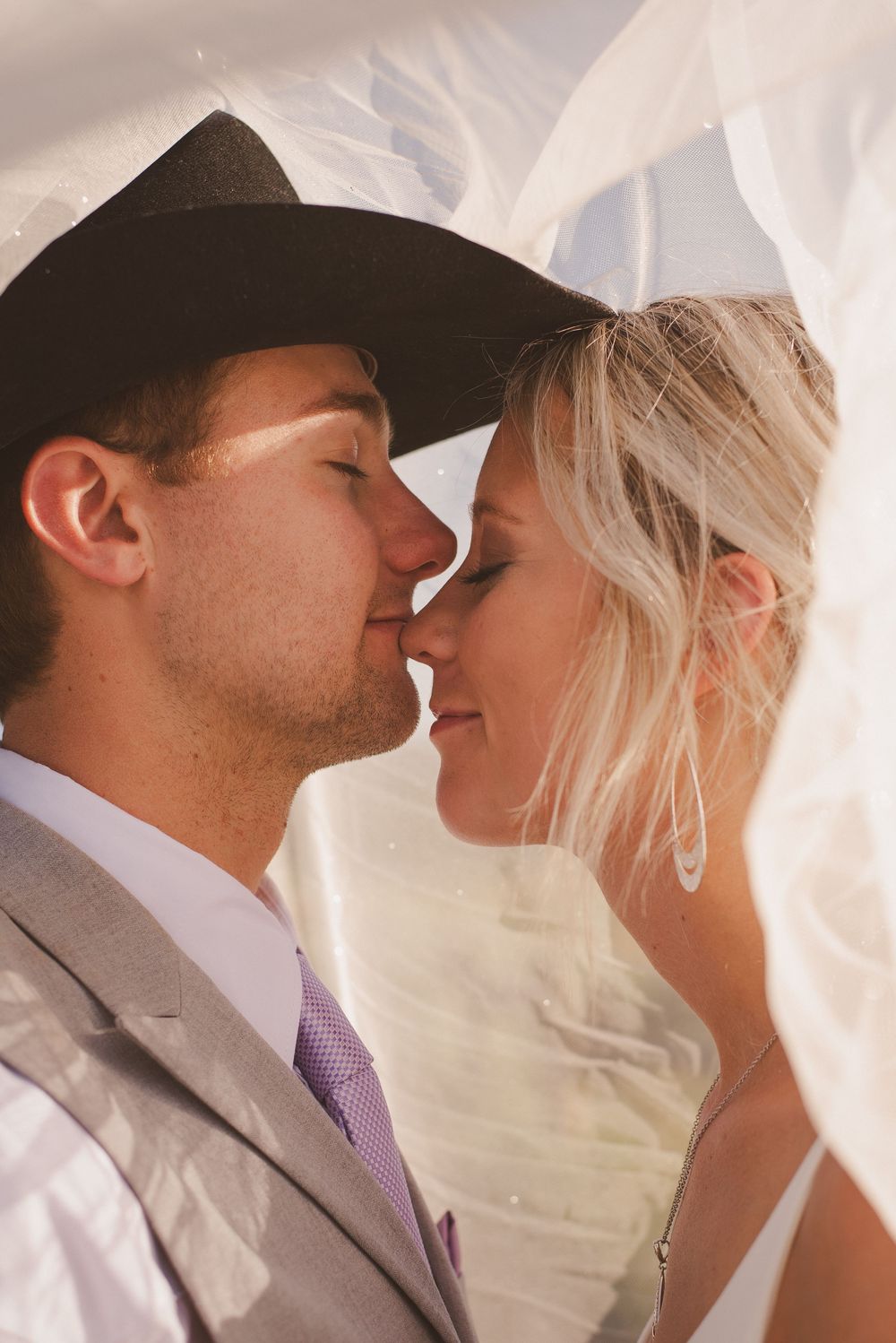 Intimate wedding portraits under flowing white veil.