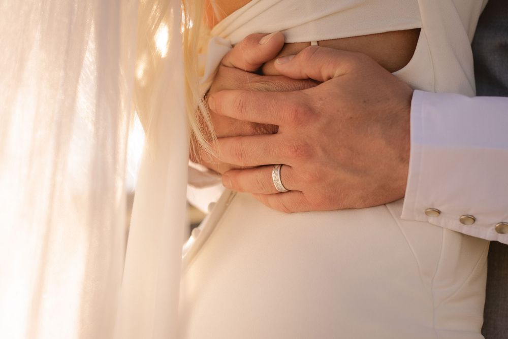 Detail shots of hands and white wedding dress fabric.