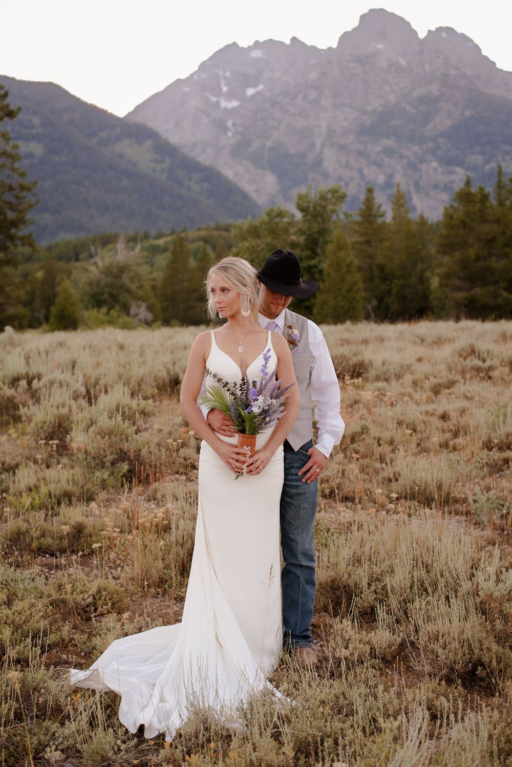 Romantic portraits in mountain meadow with wildflowers and mountain vista.