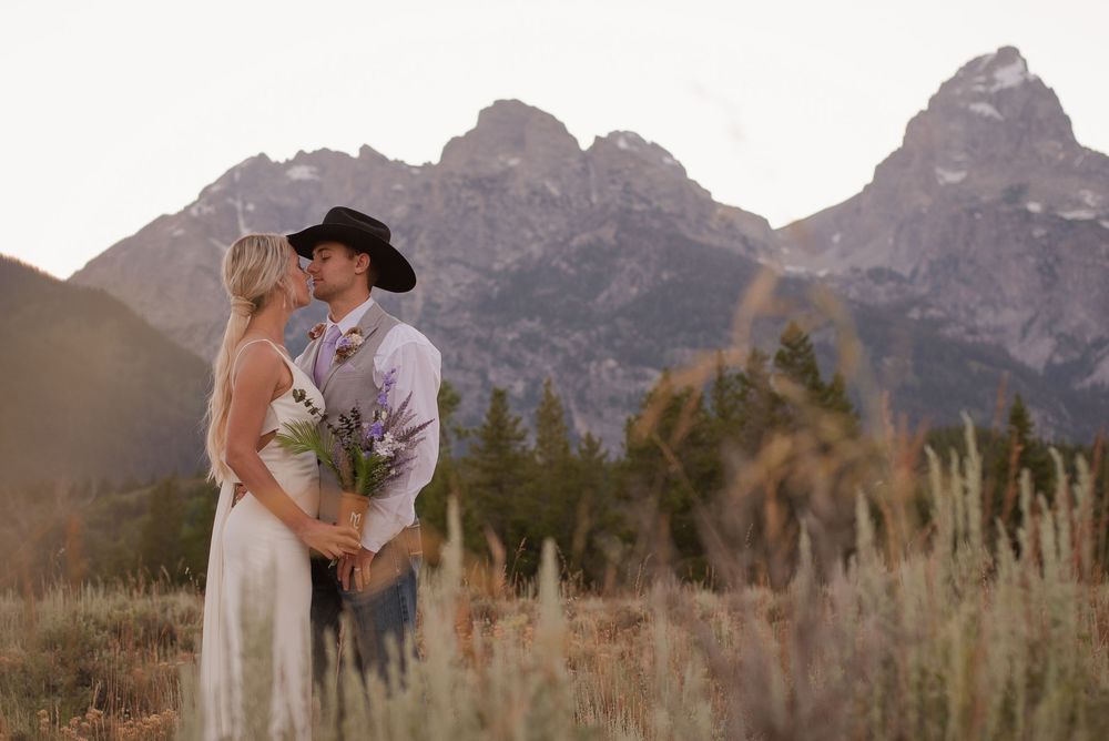 Wedding photography in mountain field with dramatic peaks in background.