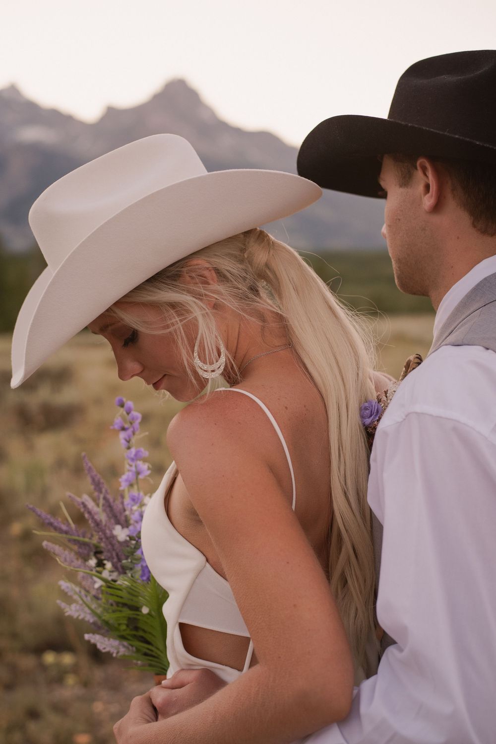 Western themed wedding portraits with cowboy hats and mountain scenery.