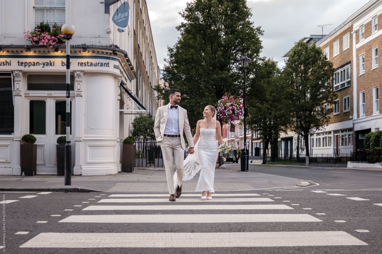 People walking on a modern urban street with white pillars and buildings in Canary Wharf, London.