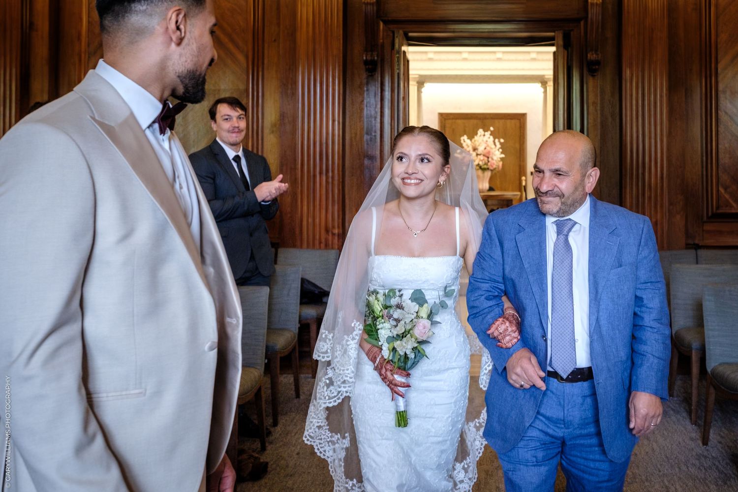 Candid moments from a wedding ceremony in a wood-paneled venue with people in formal attire and wedding party flowers.