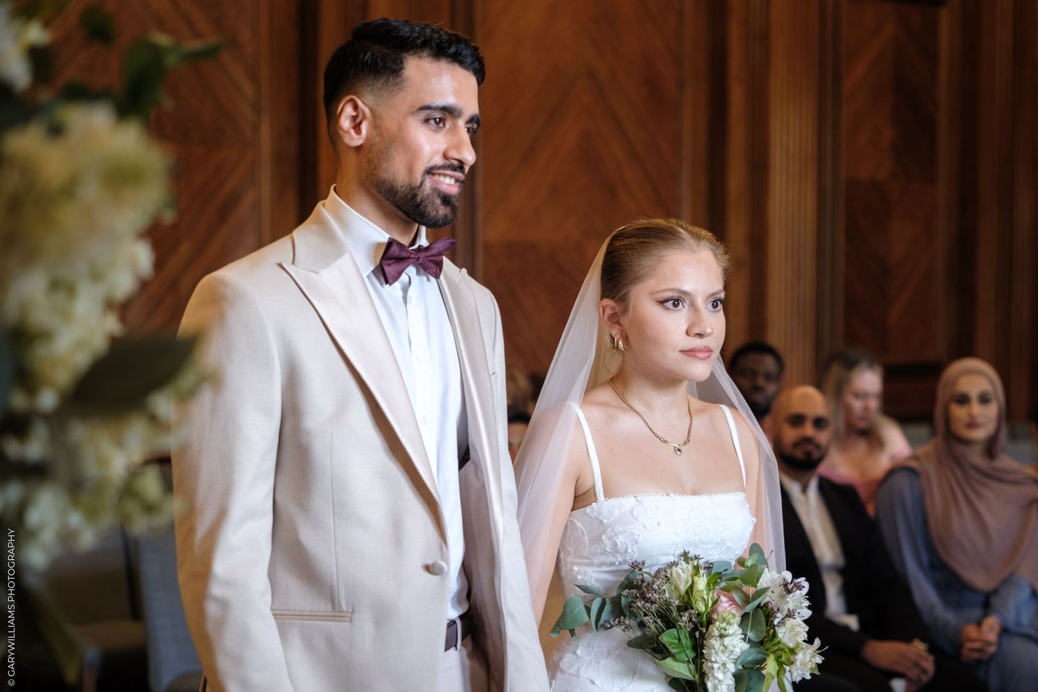 A couple shares moments on their wedding day, the groom in white suit and bride in elegant white dress with floral elements.