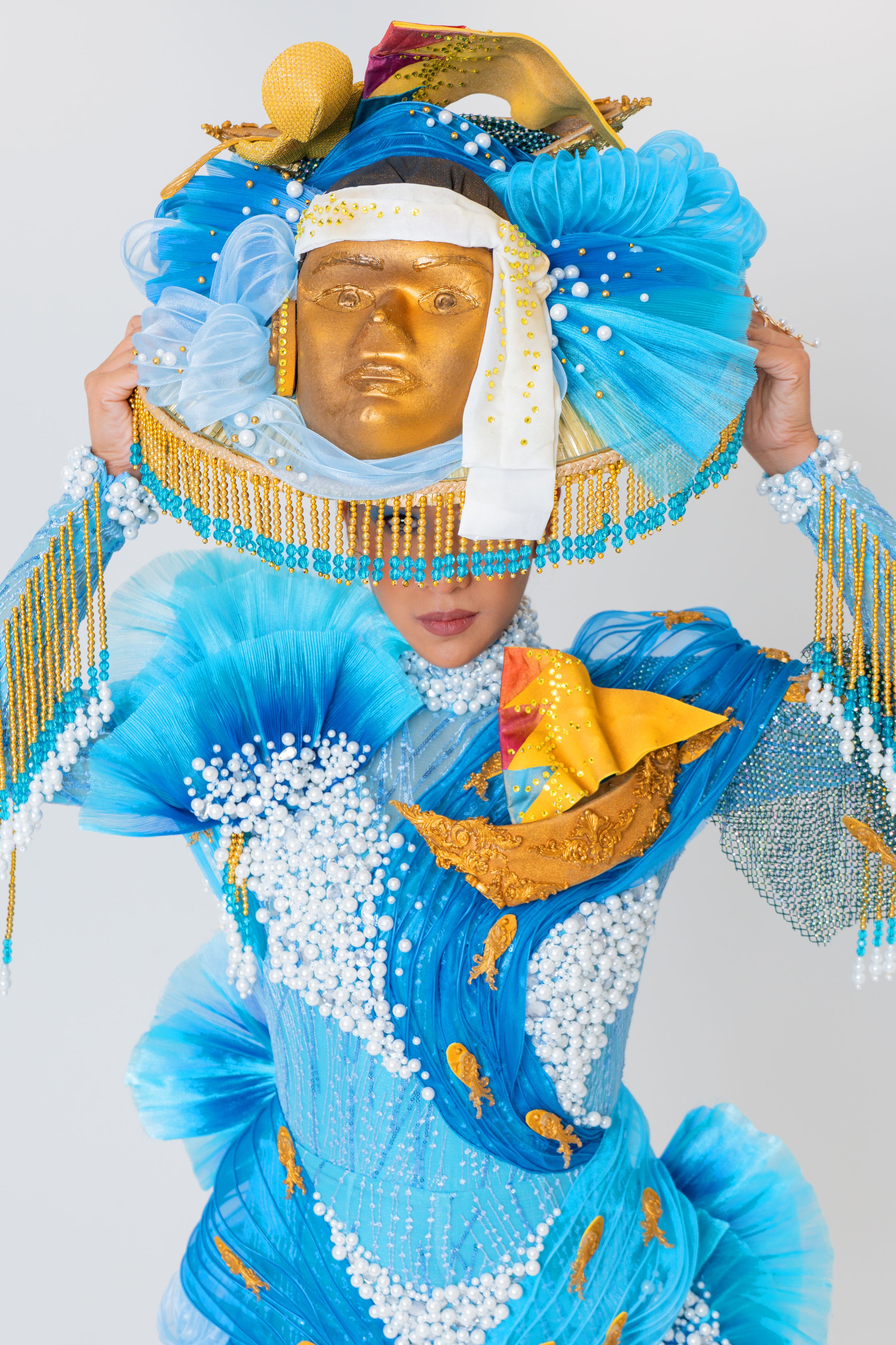 Close-up of a model wearing an intricate blue and gold national costume decorated with beads and water elements during a studio photoshoot