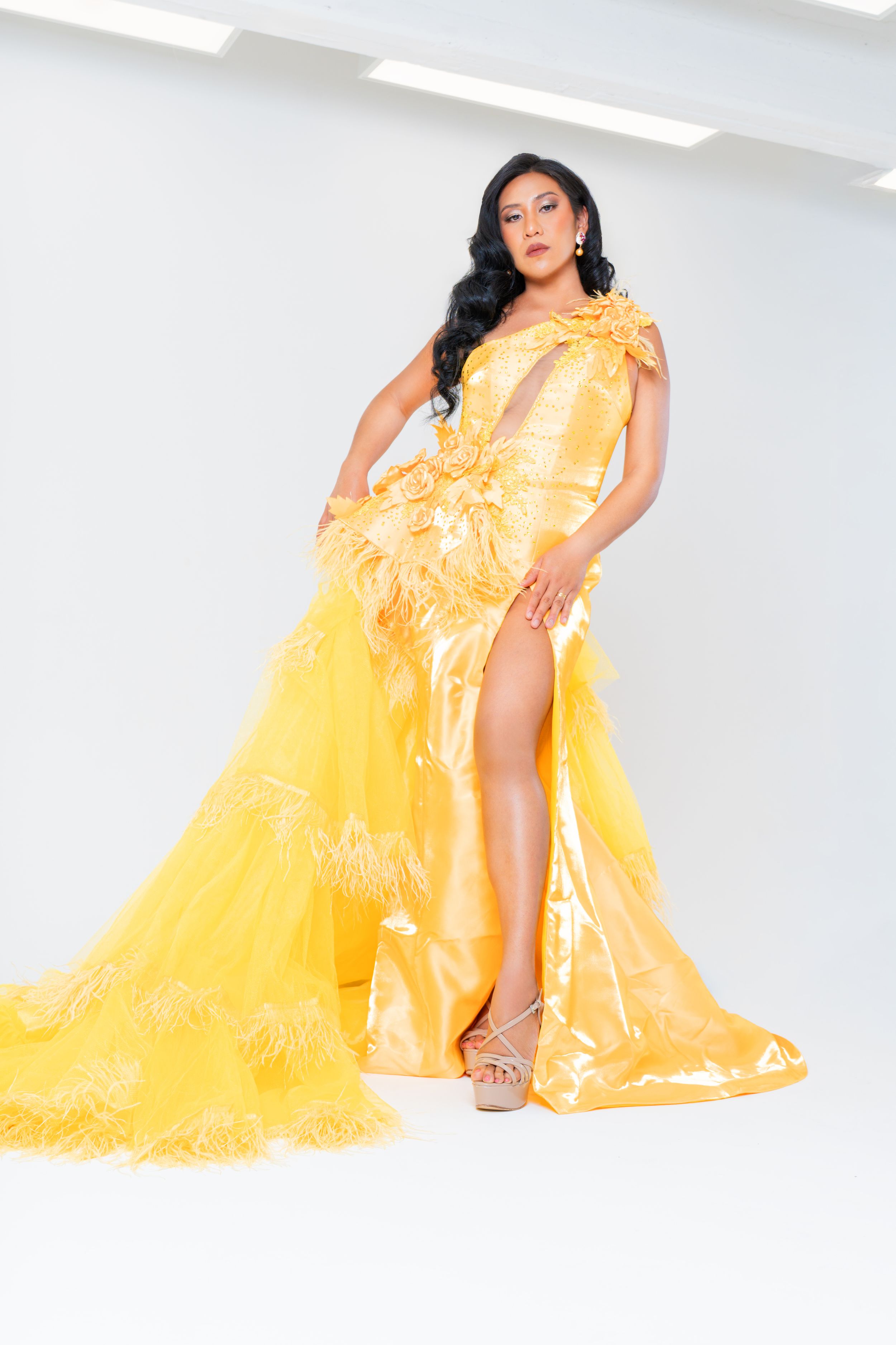 Glamorous model posing in a flowing yellow couture gown during a high-fashion studio photoshoot.