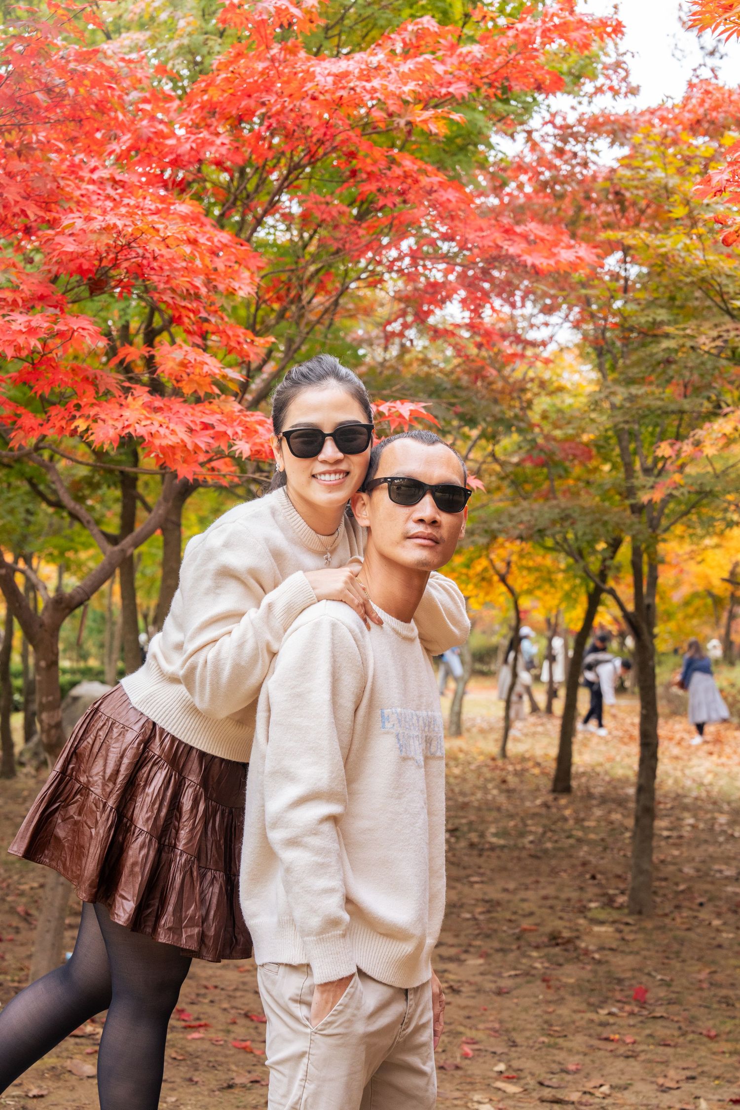 Scenic autumn landscape with vibrant red maple trees and people enjoying a stroll through the colorful fall foliage.