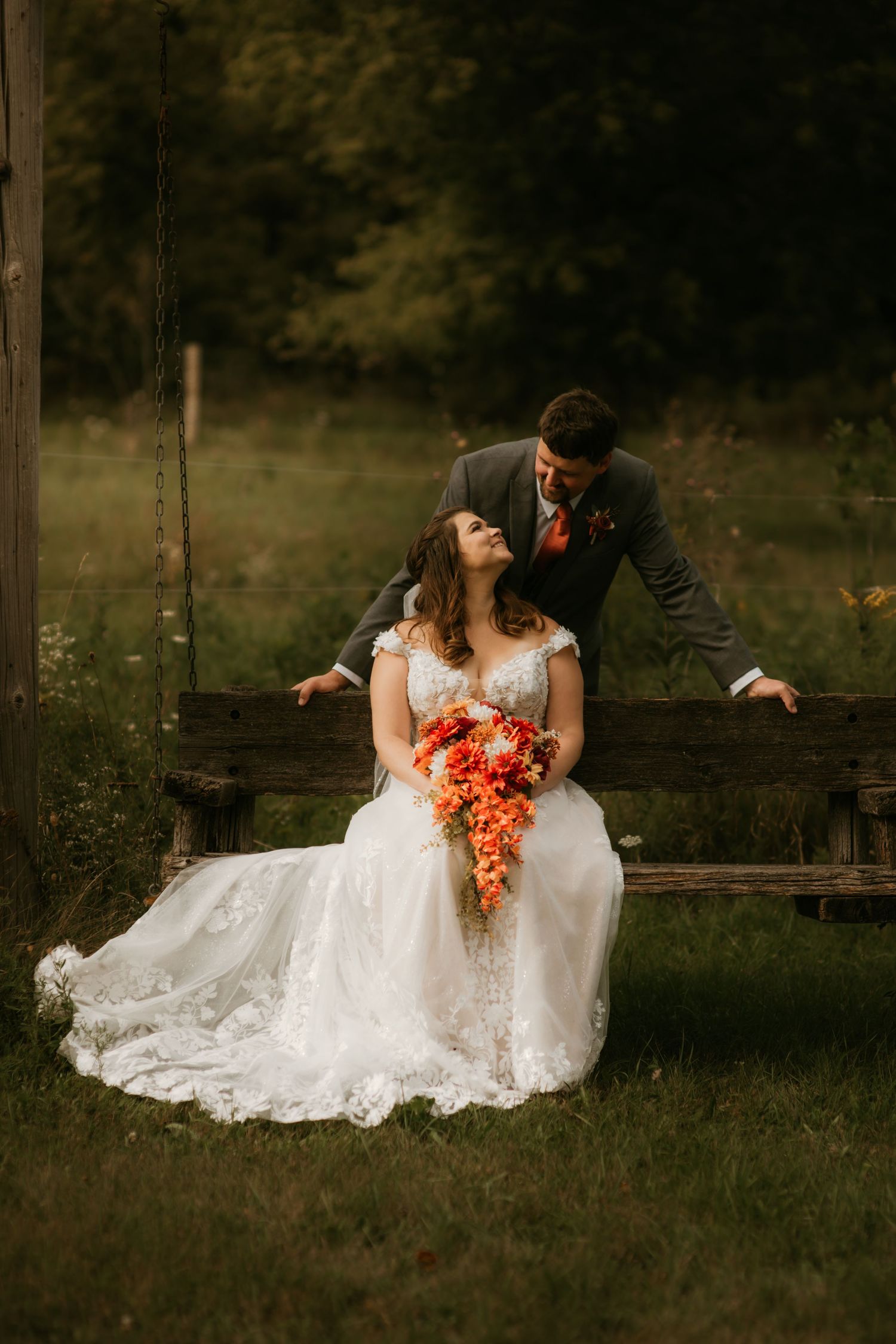 A romantic outdoor wedding photo series showing a couple sitting on rustic wooden fencing at sunset.